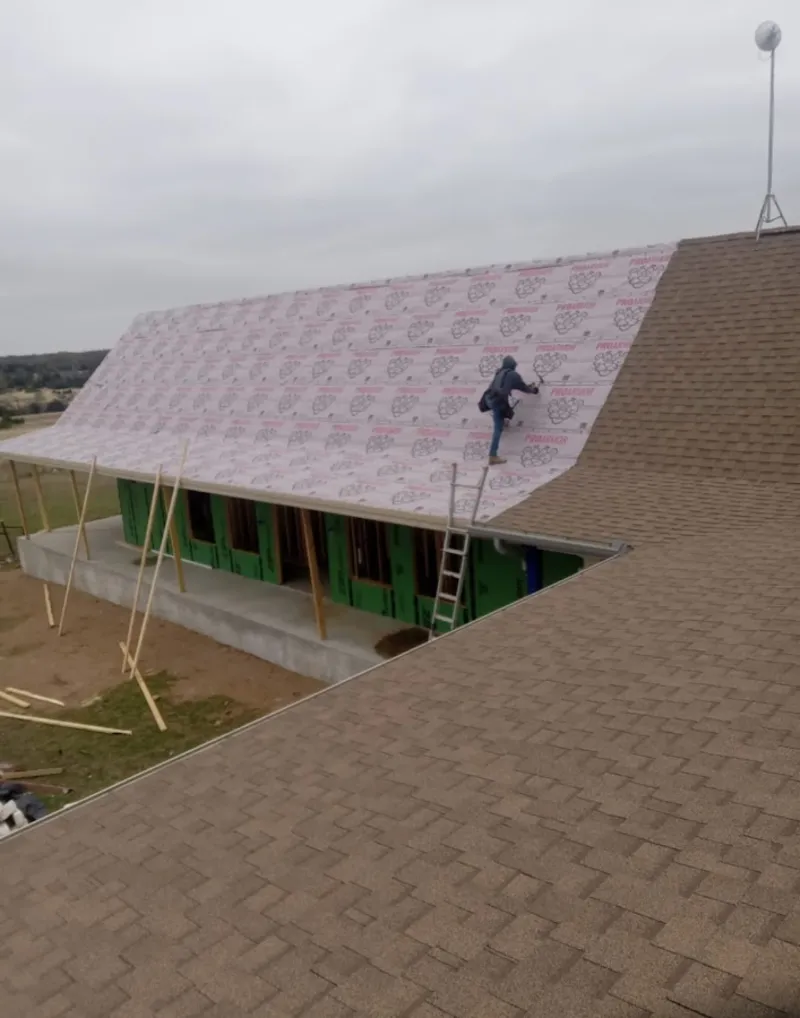 Worker preparing underlayment for a metal roof installation in Francisville